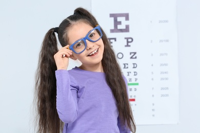 Little girl with glasses visiting children's doctor in clinic, space for text. Eye examination