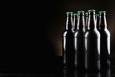 Photo of Many bottles of beer on table against dark background, space for text
