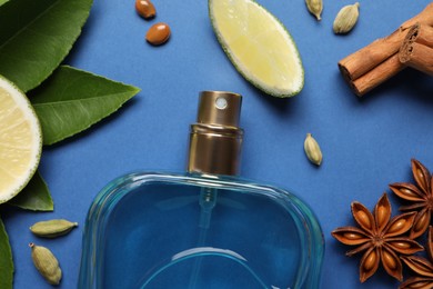 Flat lay composition with bottle of perfume and fresh citrus fruits on blue background
