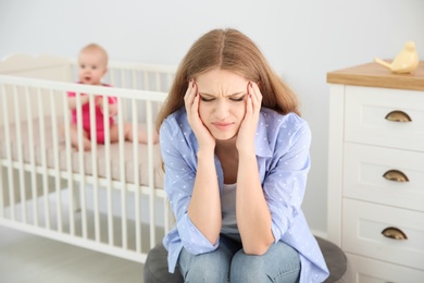 Young mother suffering from postnatal depression and little baby in room