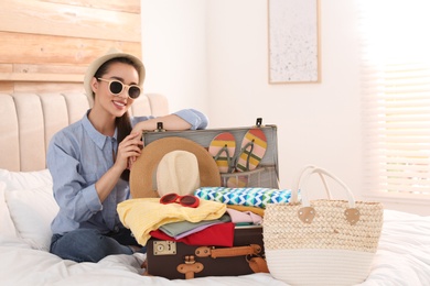Woman packing suitcase for summer vacation in bedroom