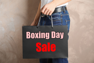 Boxing day sale. Man with shopping bag on beige background, closeup