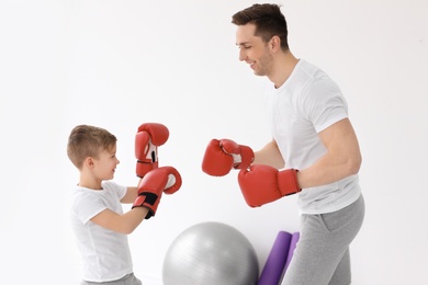 Happy dad and his son boxing in gym