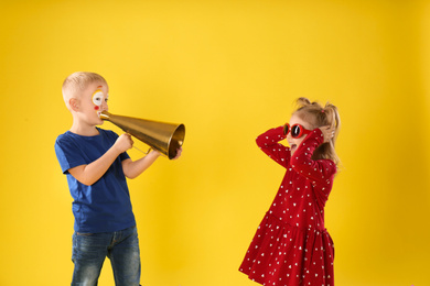 Funny kids with megaphone on yellow background. April fool's day