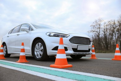 Modern car on test track with traffic cones, low angle view. Driving school