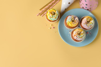 Photo of Cute sweet unicorn cupcakes and party items on yellow background, top view. Space for text