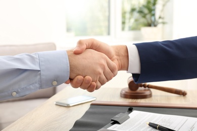 Lawyer handshaking with client over table in office, closeup