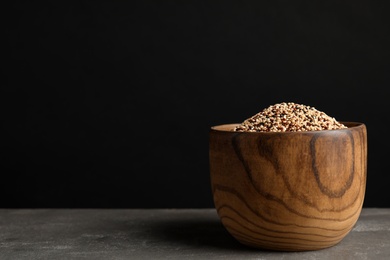 Bowl with mixed quinoa seeds on table against black background. Space for text