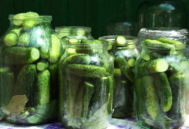 Glass jars with fresh ripe cucumbers on table. Pickling vegetables