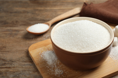Photo of Granulated sugar in bowl on wooden table