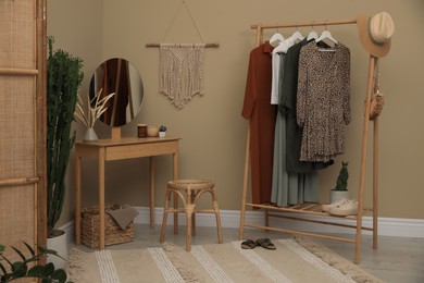 Modern dressing room interior with clothing rack, wooden table and mirror