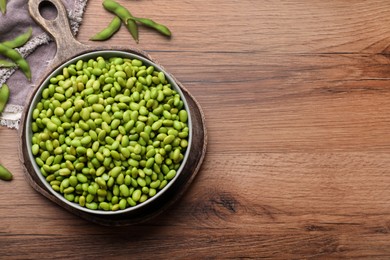 Photo of Organic edamame beans on wooden table, flat lay. Space for text