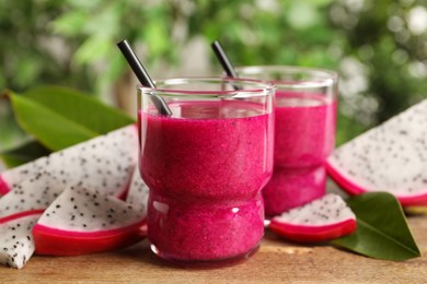 Delicious pitahaya smoothie and fresh fruits on wooden table, closeup