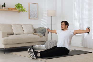 Overweight man doing exercise with dumbbells on mat at home, space for text