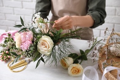 Photo of Florist making beautiful bouquet at white table, closeup