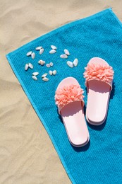Photo of Towel, seashells and flip flops on sand, above view. Beach accessories