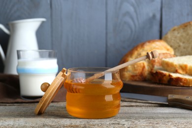 Photo of Jar of honey, milk and bread on rustic wooden table