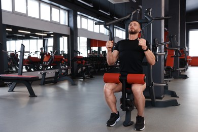 Photo of Man training with professional machine in gym