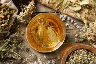 Freshly brewed tea and dried herbs on wooden table, flat lay