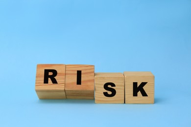 Wooden cubes with word Risk on light blue background