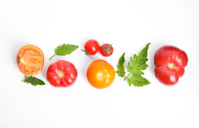 Many different ripe tomatoes and leaves on white background, flat lay