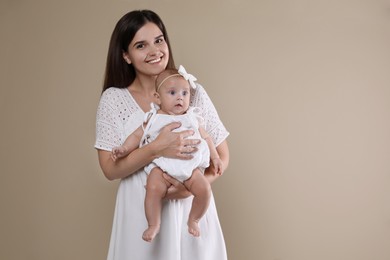 Beautiful mother with her cute baby on beige background. Space for text