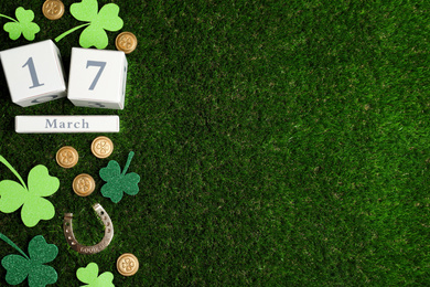 Flat lay composition with horseshoe and wooden block calendar on grass, space for text. St. Patrick's Day celebration