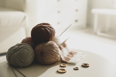 Yarn balls, buttons and knitting needles on white table indoors, space for text. Creative hobby