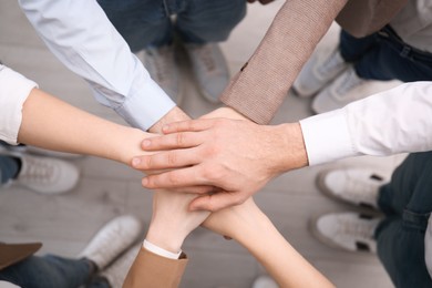 People holding hands together in office, top view
