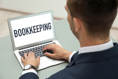 Bookkeeping concept. Man working with laptop at grey table, closeup