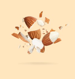 Pieces of tasty almonds falling on beige background