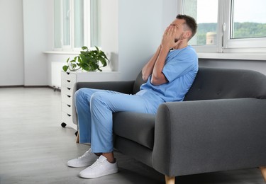 Photo of Exhausted doctor covering face on sofa in hospital