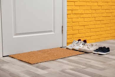 Stylish shoes and mat near door in hallway