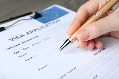 Woman filling visa application form for immigration to European Union at table, closeup