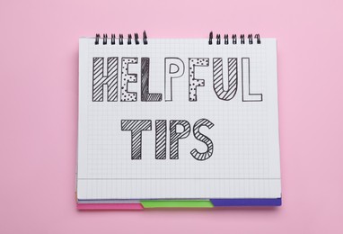 Photo of Phrase Helpful Tips in notebook on pink background, top view