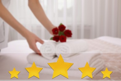 Chambermaid putting flowers with fresh towels bed in five star hotel room, closeup, closeup