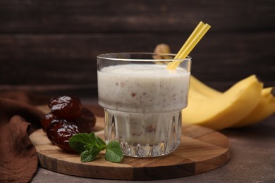 Photo of Glass of delicious date smoothie, mint and dried fruits on brown table