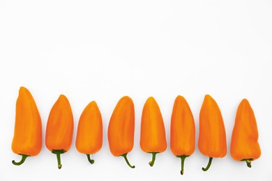 Photo of Fresh raw orange hot chili peppers on white background, top view. Space for text