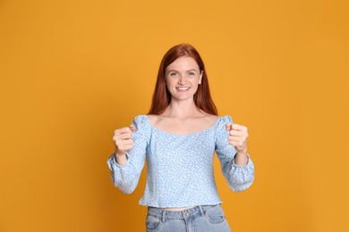 Happy young woman pretending to drive car on yellow background
