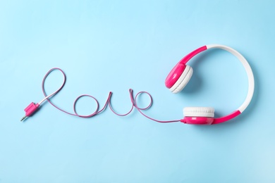 Word Love made with cable of headphones on light blue background, top view. Listening music songs 
