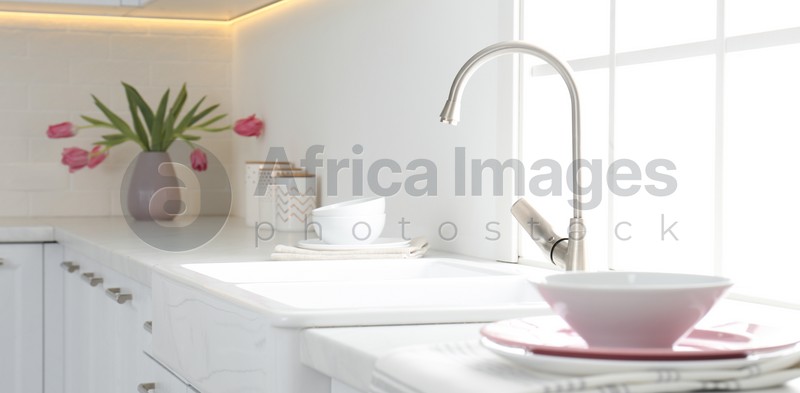 Image of Beautiful ceramic dishware and bouquet on countertop in kitchen. Banner design