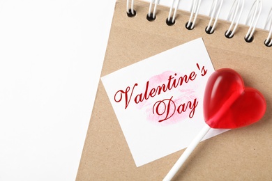 Happy Valentine's Day. Heart shaped lollipop, notebook and paper note with lipstick kiss on white background, flat lay