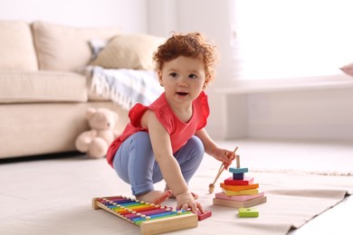 Photo of Cute little child playing with toys on floor at home