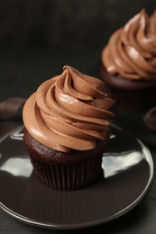 Delicious fresh chocolate cupcake on saucer, closeup