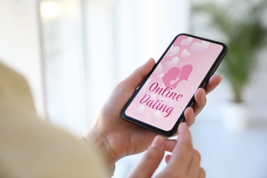 Woman visiting dating site via smartphone indoors, closeup
