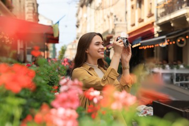 Photo of Young woman with camera taking photo on city street. Interesting hobby