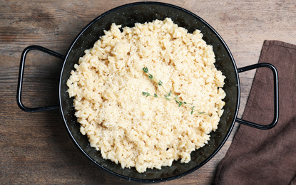 Photo of Delicious risotto with cheese on wooden table, top view