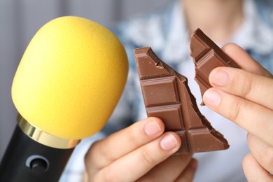 Woman making ASMR sounds with microphone and chocolate, closeup