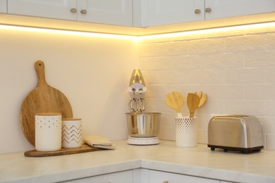 Photo of Modern toaster, mixer and utensils on counter in kitchen
