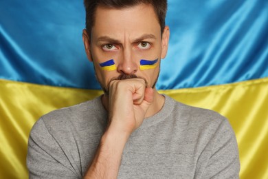 Photo of Angry man with face paint near Ukrainian flag